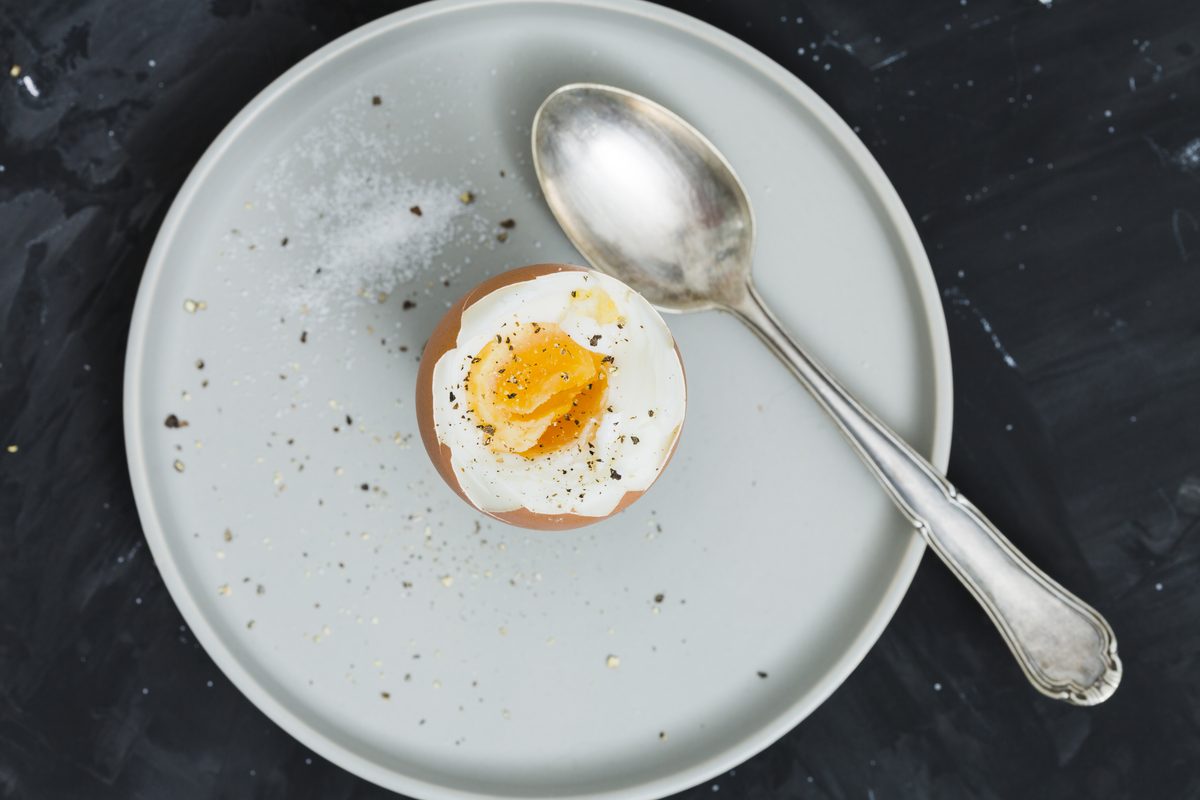 Soft-boiled egg opened on a plate with a spoon
