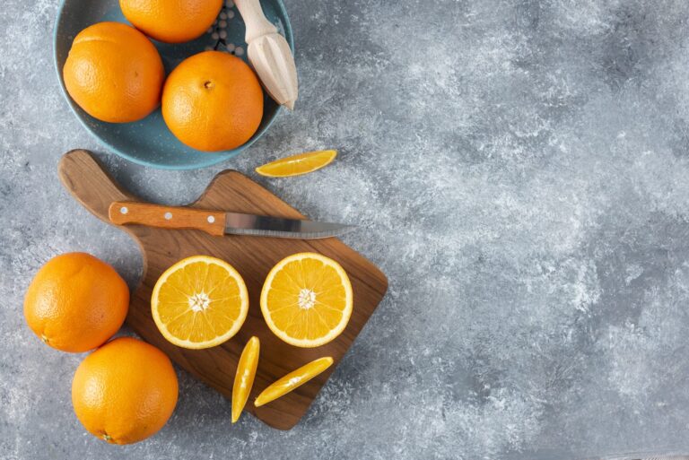 Whole and sliced oranges on a wooden board