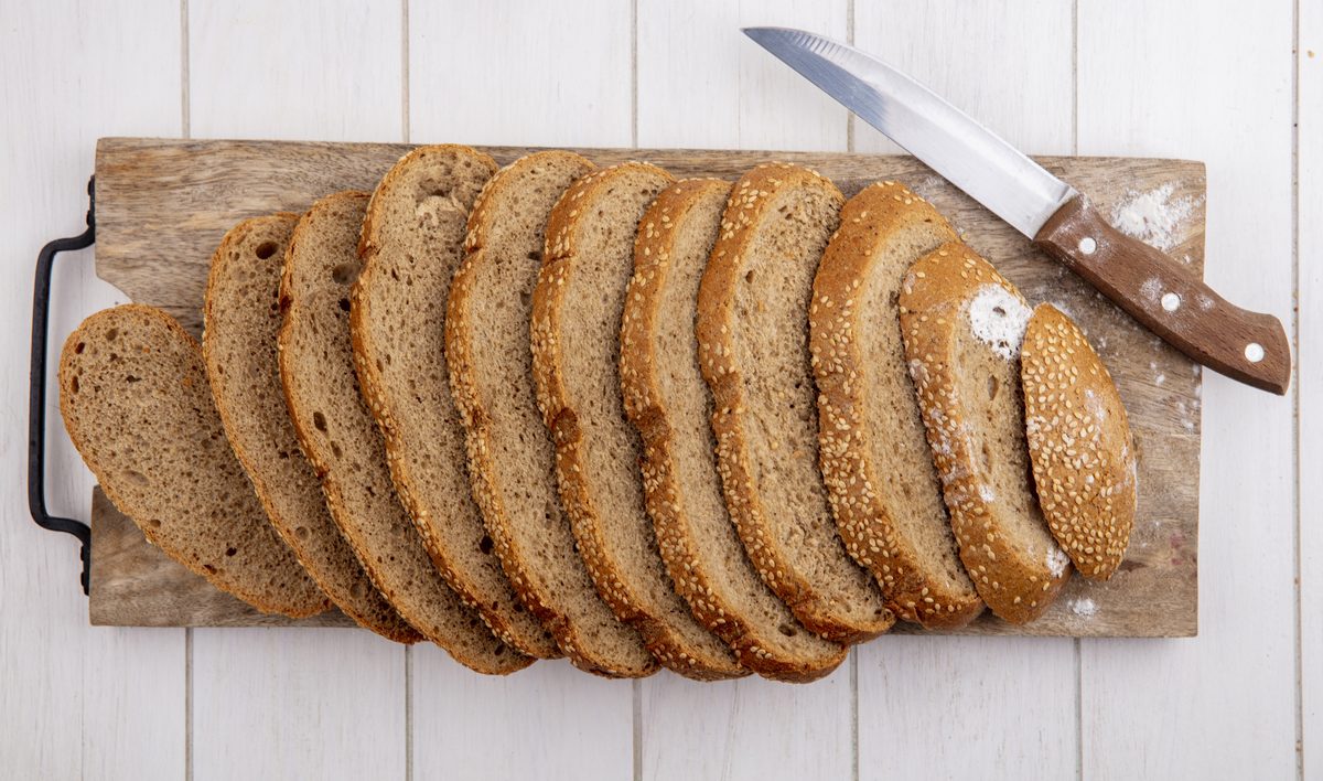 Sliced seeded wholemeal bread on a board with a knife