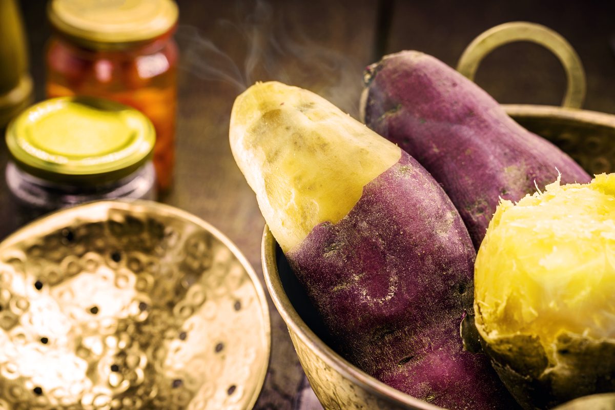 Purple-skinned sweet potatoes steamed in a brass basin