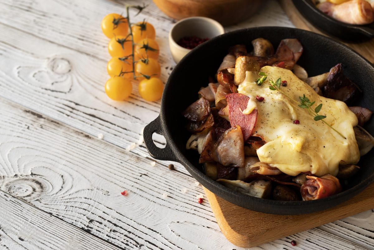 Raclette pan melted over potatoes and cured meats