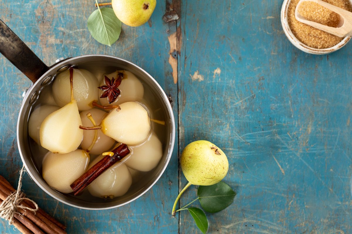 Pears poached in spiced syrup with cinnamon and star anise in a saucepan