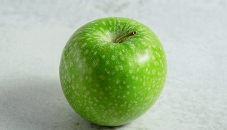 Whole green apple on a grey background
