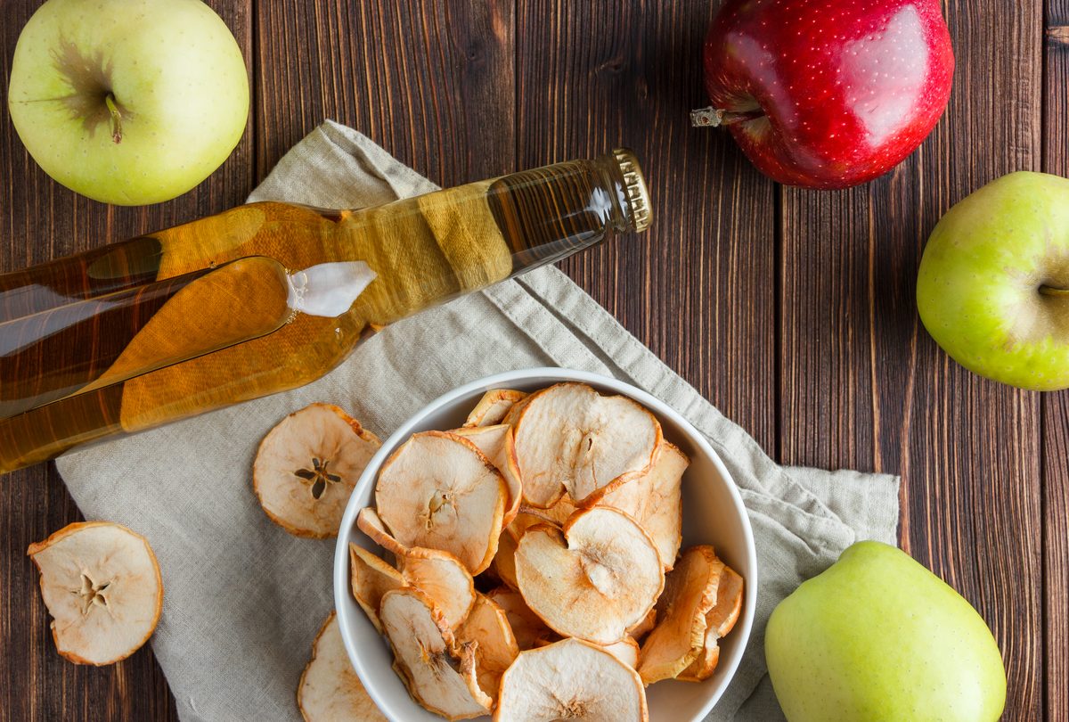 Fresh apples, bottled apple juice and a bowl of dried apple chips