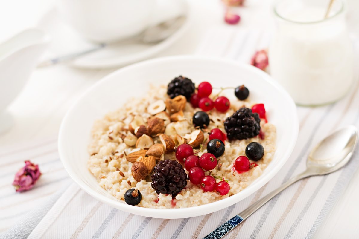 Porridge topped with blackberries, redcurrants and crushed hazelnuts in a white bowl