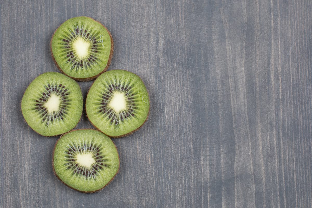 Four slices of kiwi on a grey wooden table