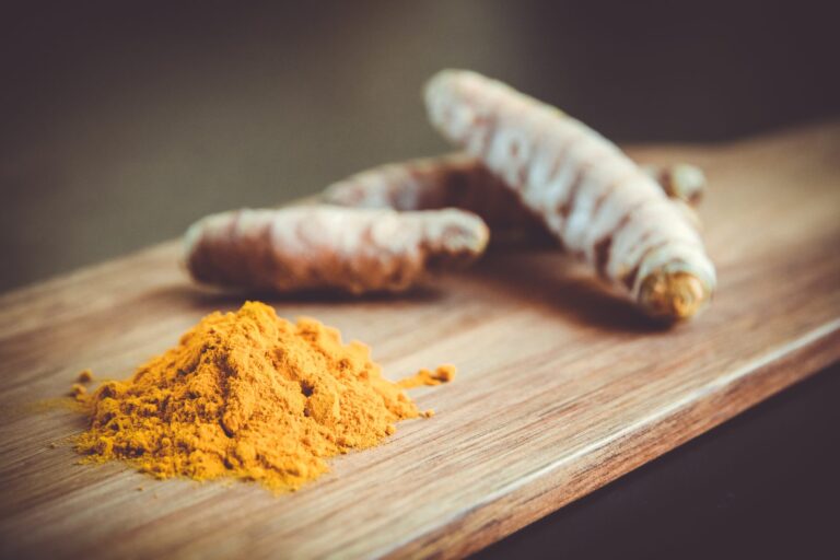Turmeric root and ground turmeric on a wooden board