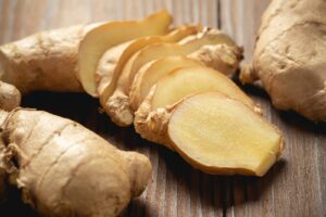 Racine de gingembre frais entière et en tranches sur une table en bois