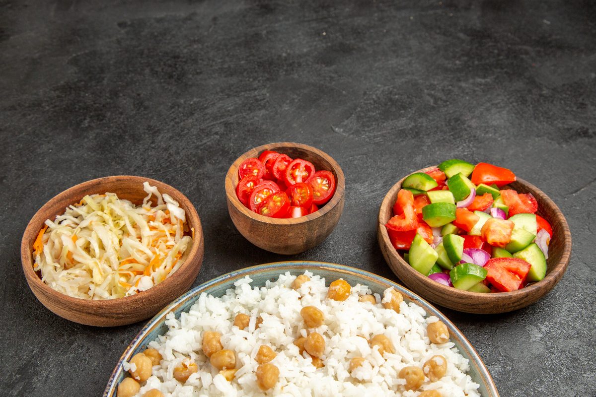 White rice with chickpeas served with bowls of raw vegetables