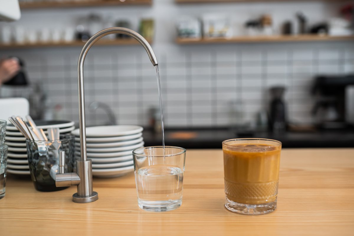 Robinet de cuisine et verre d'eau sur un comptoir en bois