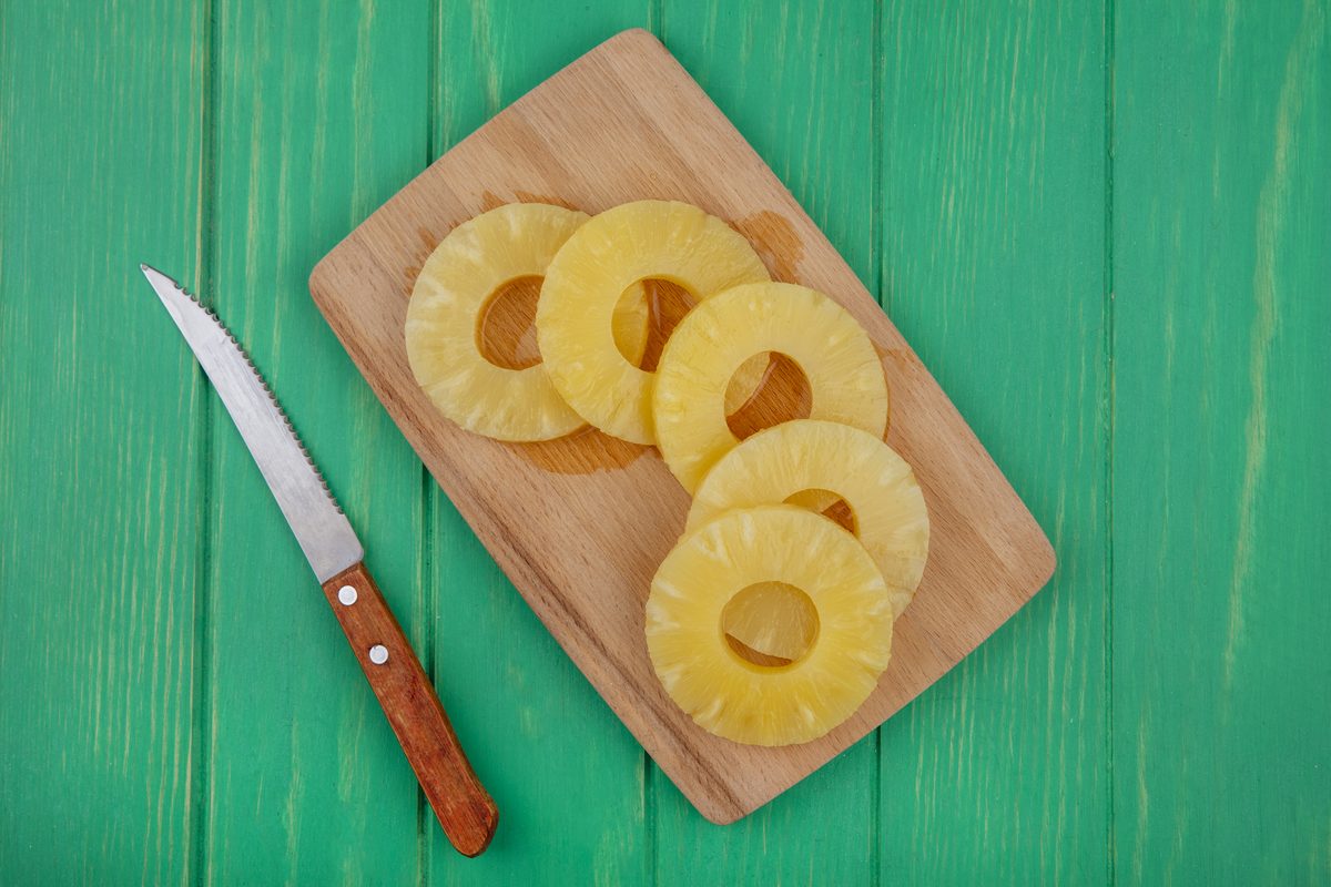 Fresh pineapple rings on a chopping board with a knife