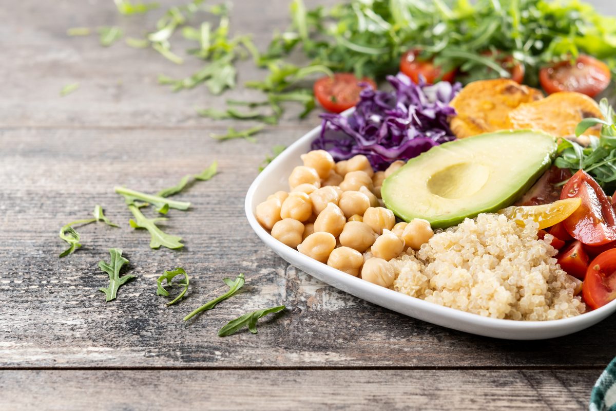 Salade composée de pois chiches, avocat, quinoa et tomates sur une table en bois