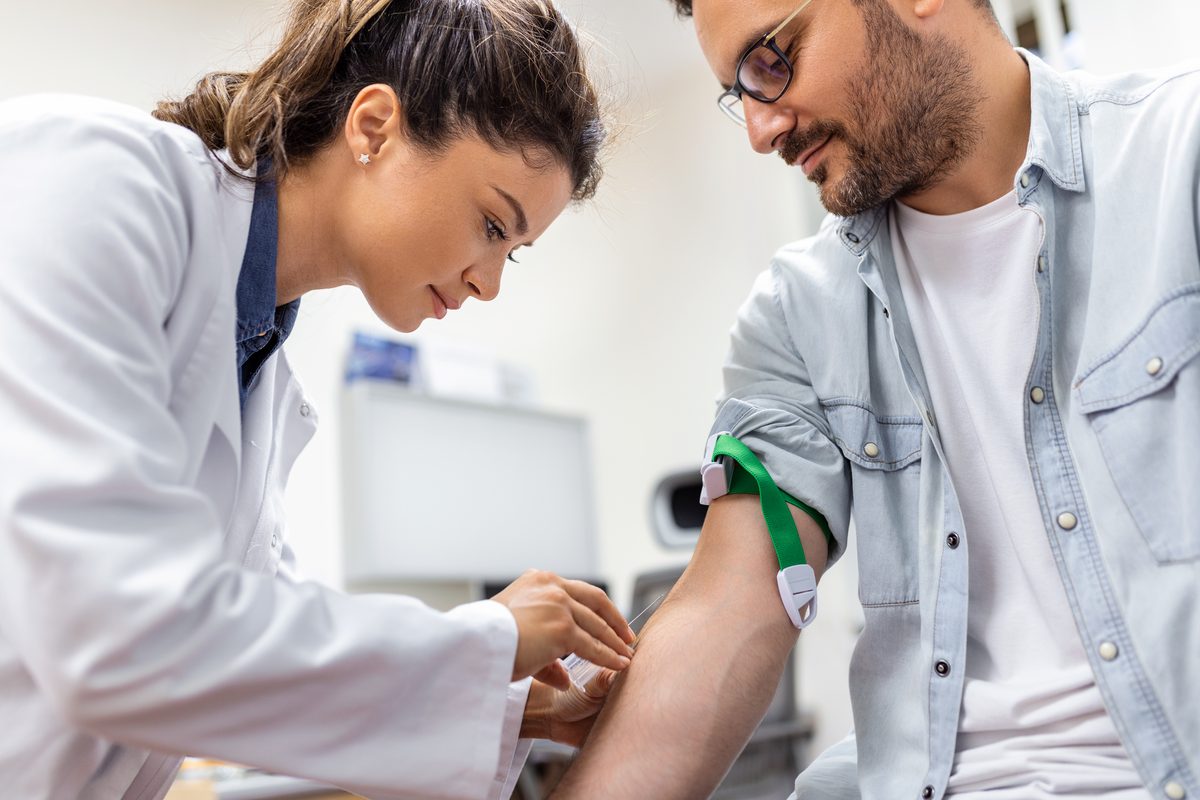 Soignante qui réalise une prise de sang au bras d'un patient