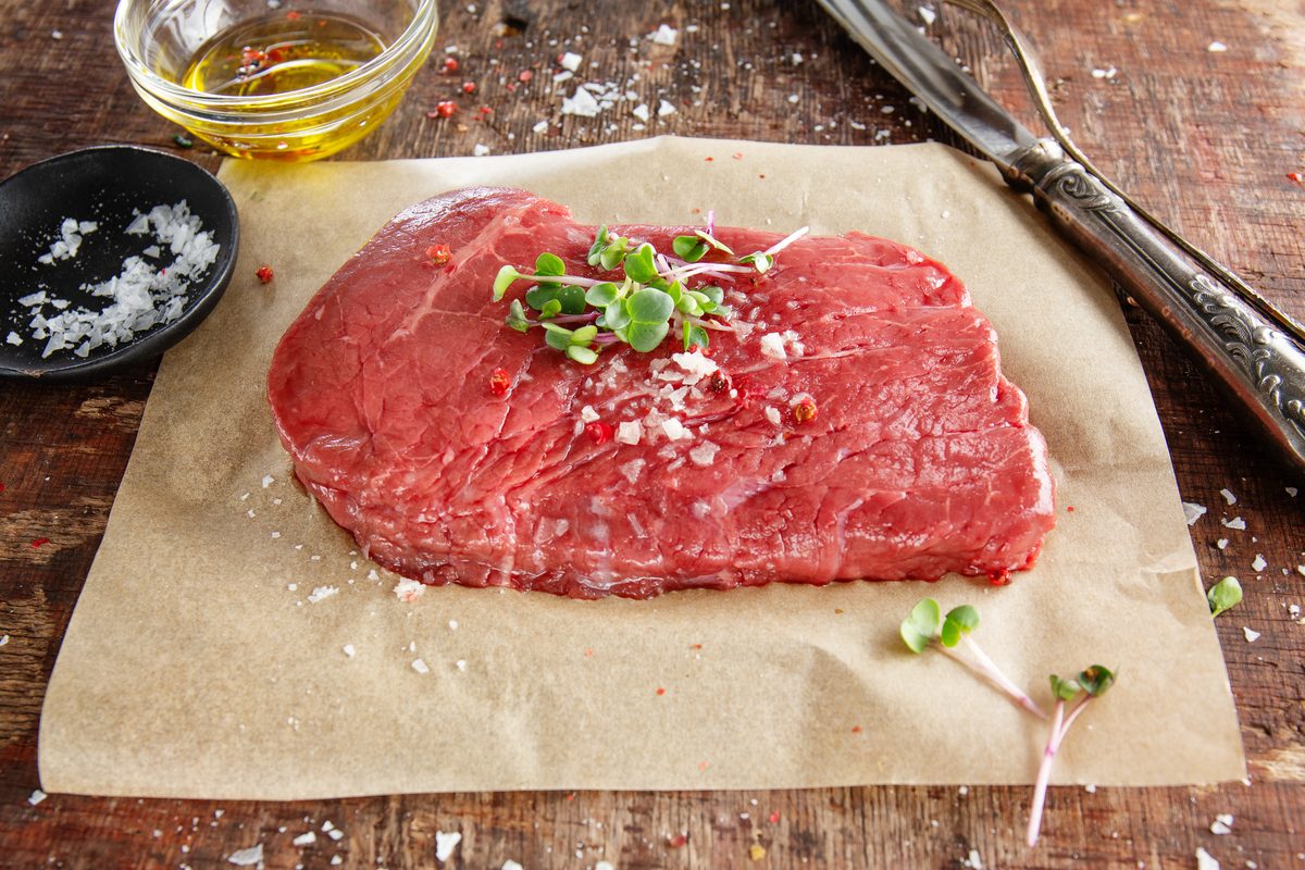Steak de viande rouge crue sur une vieille planche en bois