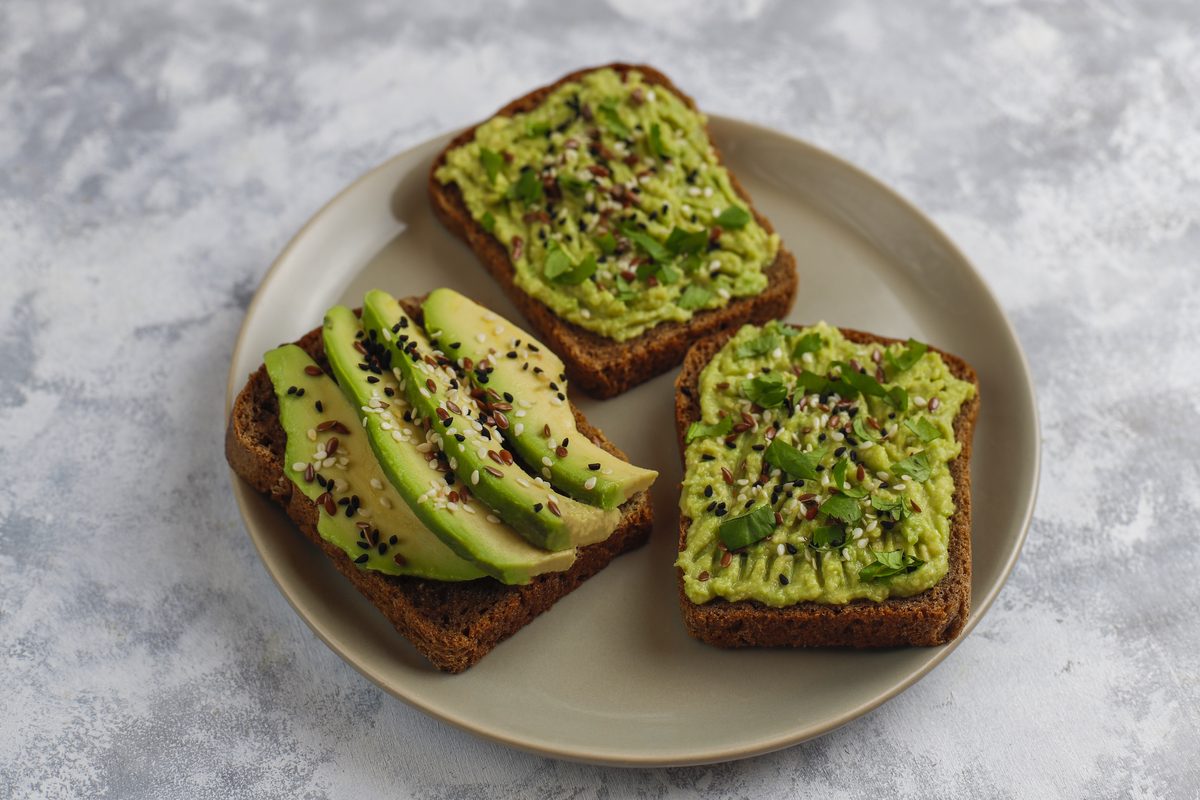Dark bread toasts with avocado sprinkled with sesame and flax seeds