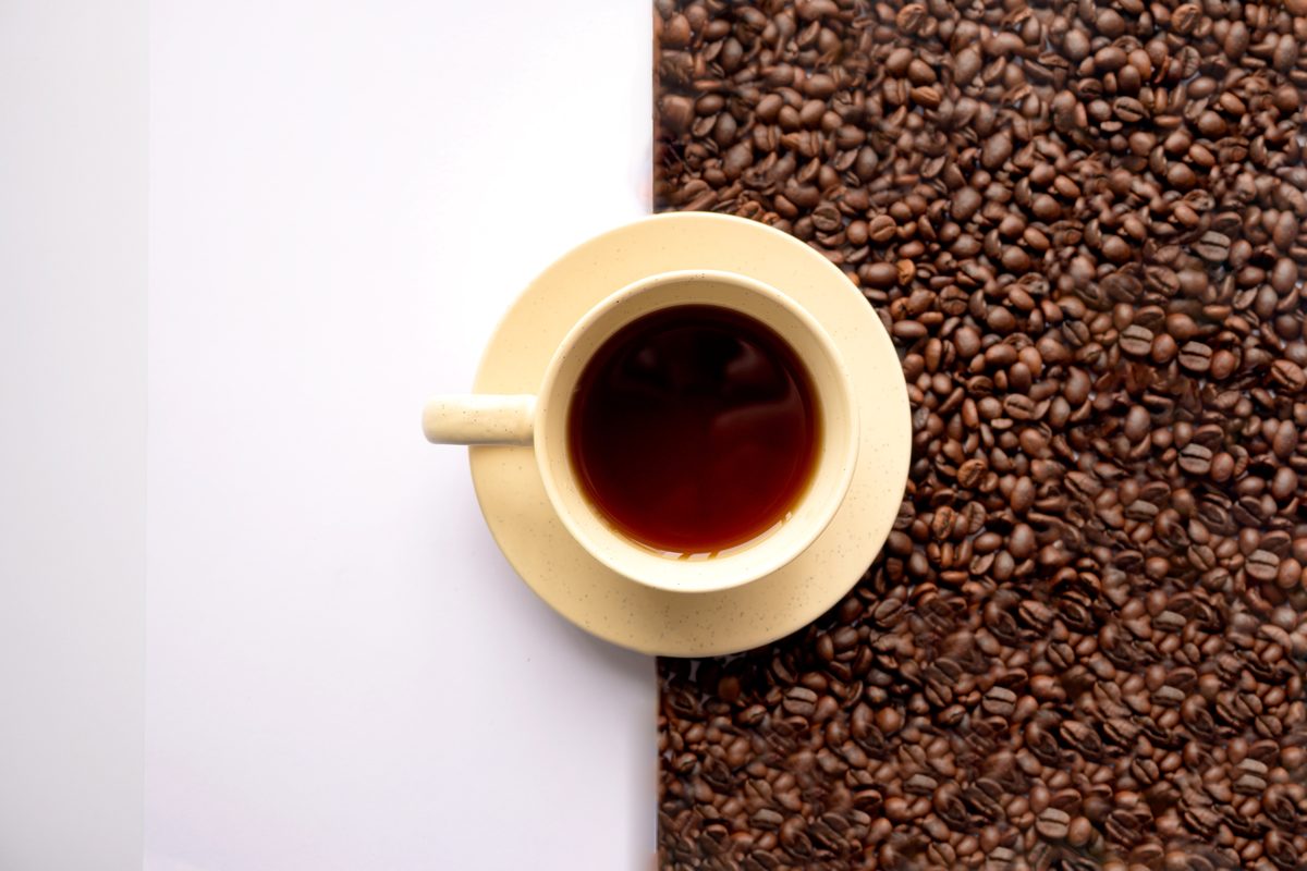 Cup of black coffee and coffee beans on a white background
