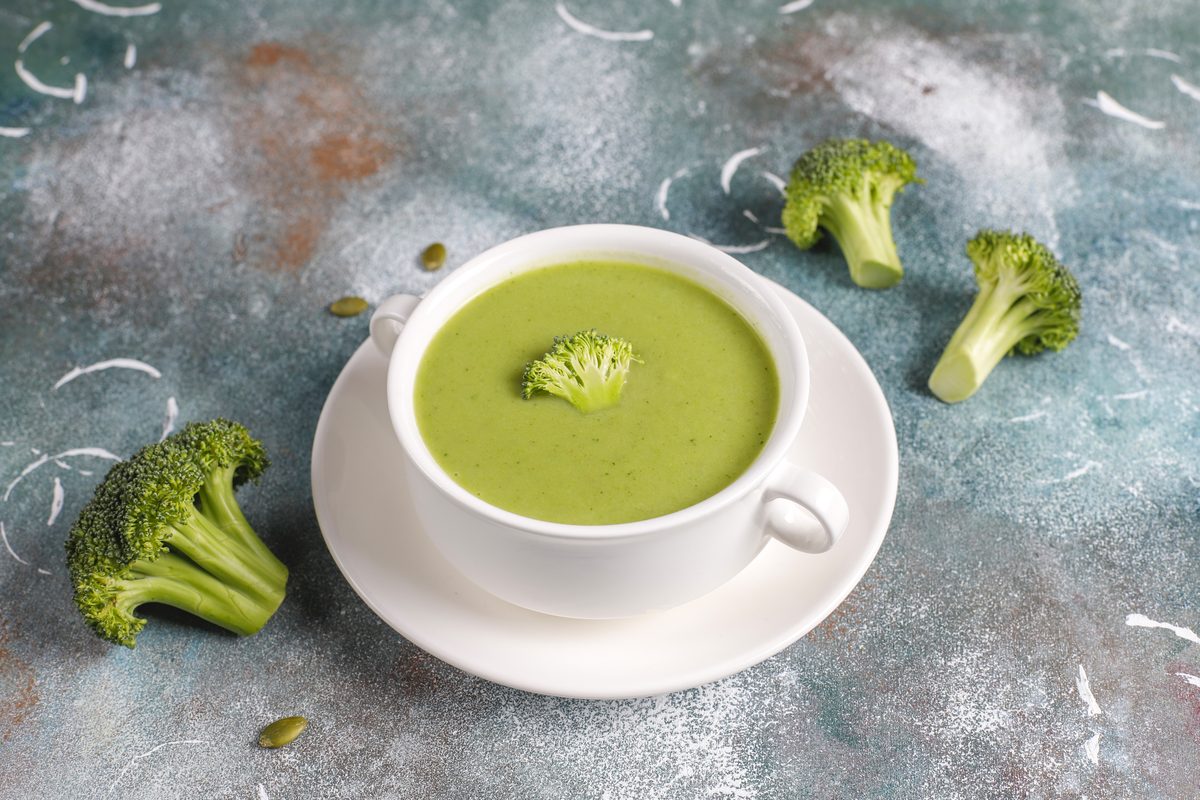 Tasse de velouté de brocoli entourée de bouquets de brocoli