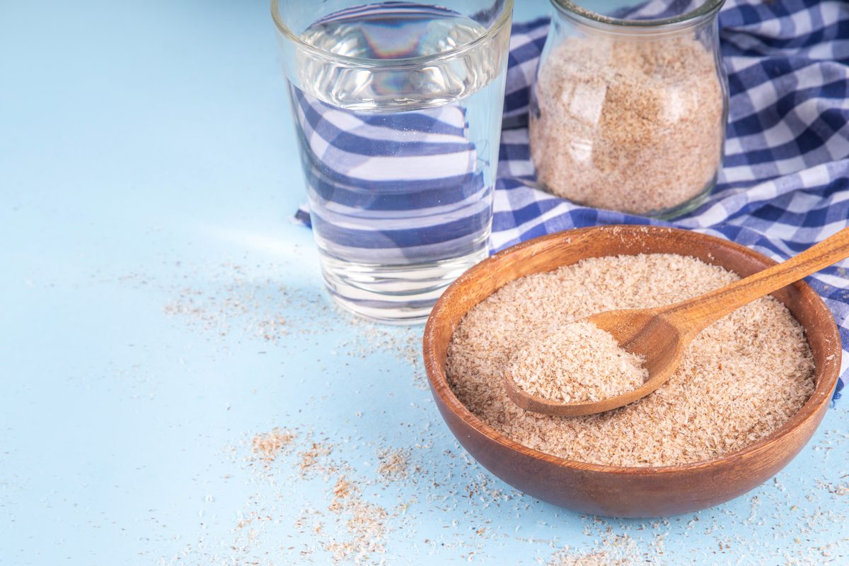 Blond psyllium husks in a spoon, a bowl and a jar with a glass of water