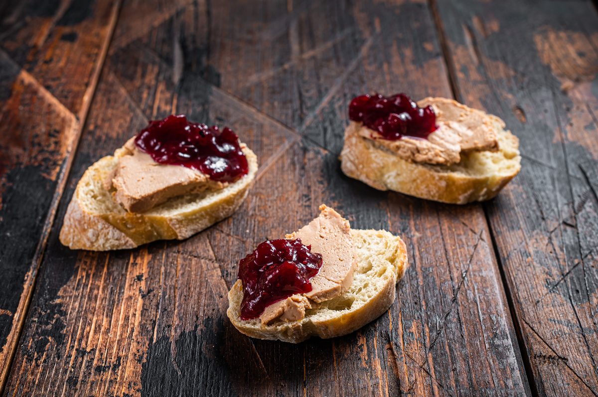 Foie gras toasts topped with cranberry jam on a wooden table