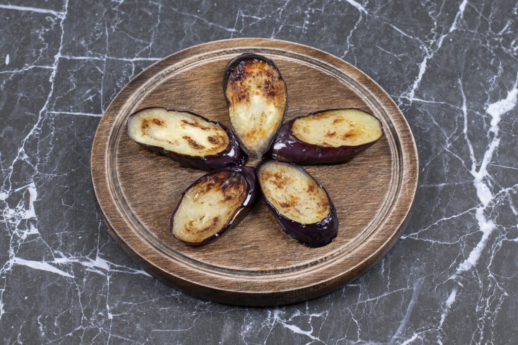 Pan-fried aubergine slices on a wooden board