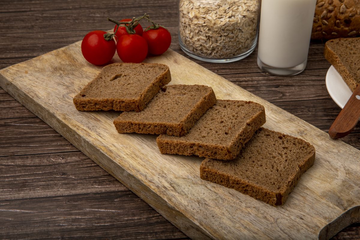 Slices of rye bread on a board with cherry tomatoes