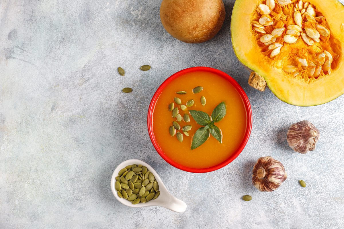 Pumpkin soup sprinkled with pumpkin seeds in a red bowl