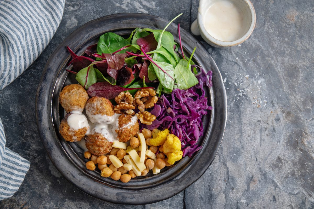 Plate of falafels, chickpeas, red cabbage and baby salad leaves with white sauce