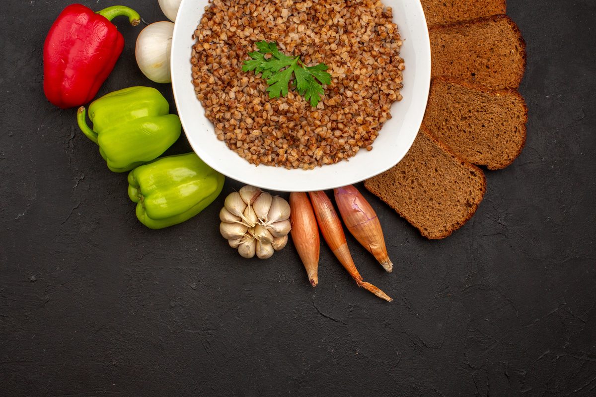 Plate of cooked buckwheat with slices of wholemeal bread, peppers and carrots