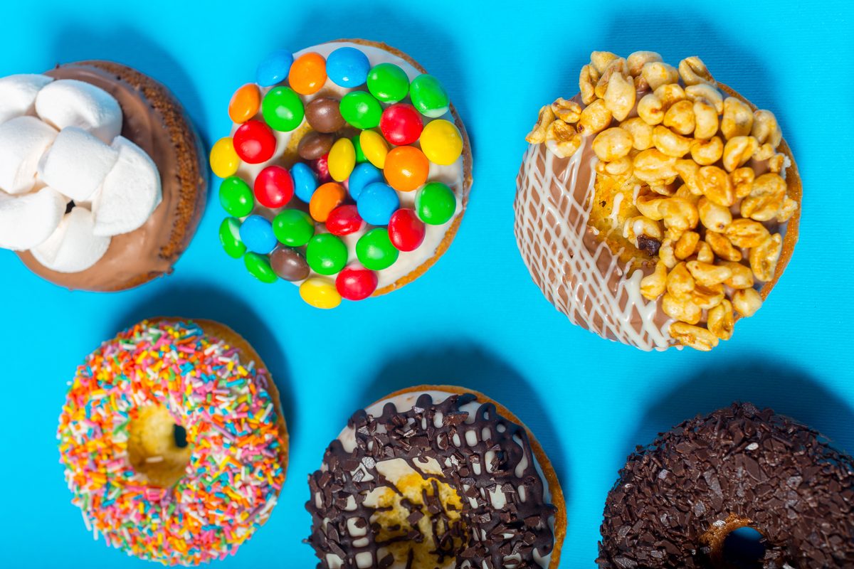 Iced doughnuts topped with sweets, marshmallows and popcorn on a blue background