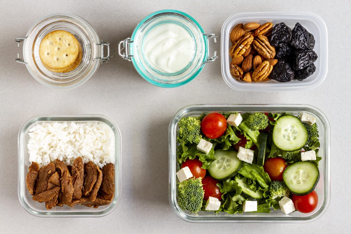Meal prep boxes: rice and meat, salad, yoghurt, walnuts and prunes