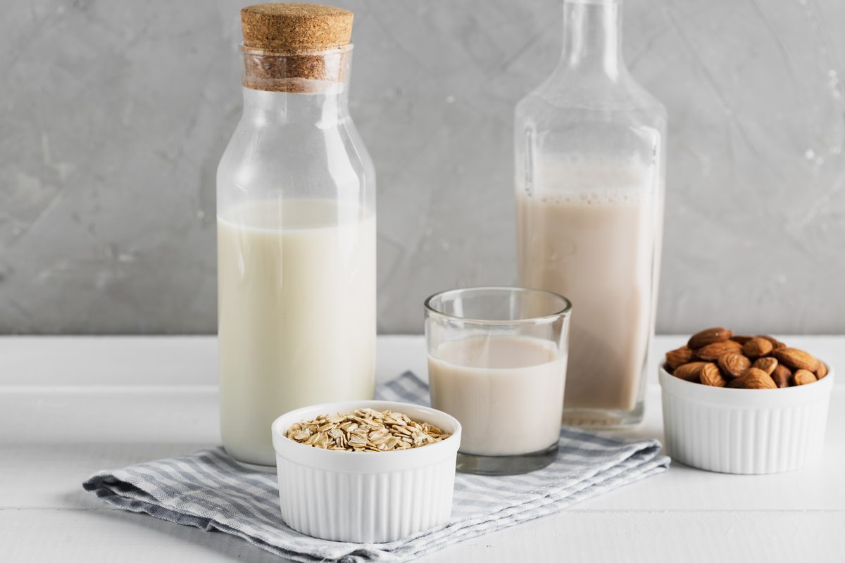 Carafes of oat and almond drinks with oat flakes and almonds in small bowls