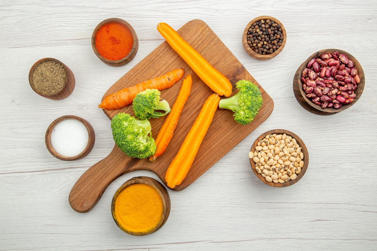 Carottes, brocoli, haricots secs et pois chiches autour d'une planche à découper