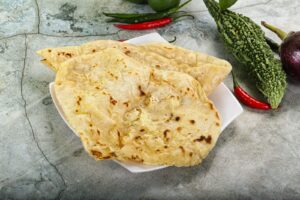 Cheese naan dorés servis dans une assiette blanche avec des piments