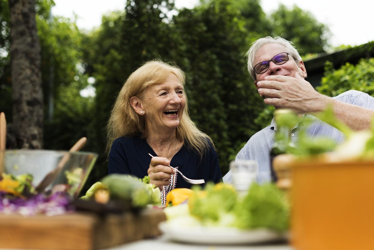Couple de seniors partageant une salade de légumes frais au jardin