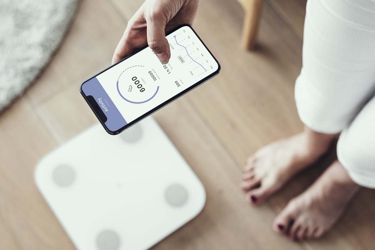 Woman checking her weight on an app next to a smart scale