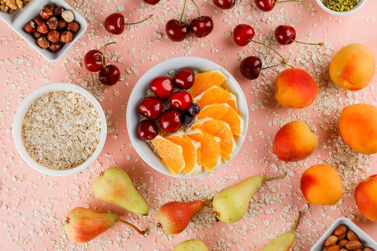 Oat flakes, cherries, orange, apricots and pears on a pink background