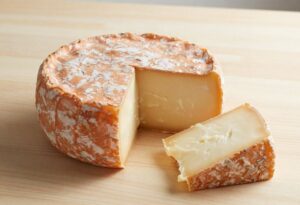 Tartiflette cheese with an orange rind and a slice cut