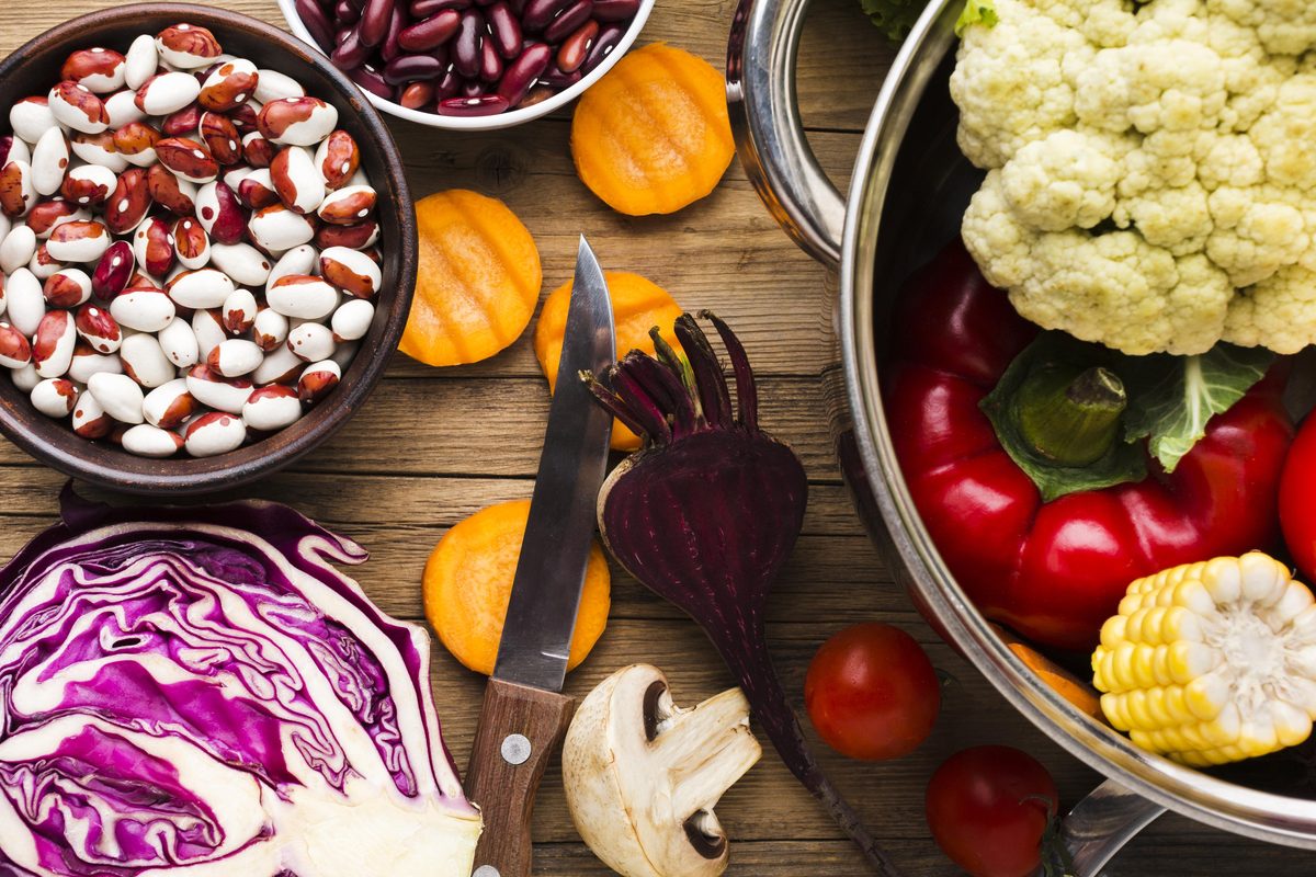 Dried beans, red cabbage, beetroot, cauliflower, peppers and sweetcorn on a wooden table