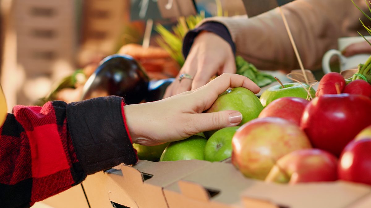 Hand choosing an apple from a fruit stall at the market