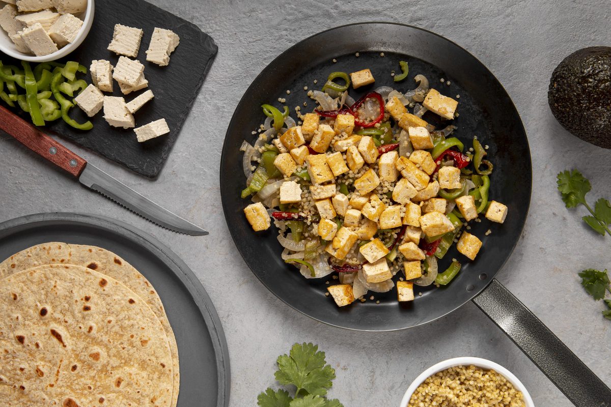 Pan-fried diced tofu with peppers and onions next to wheat pancakes