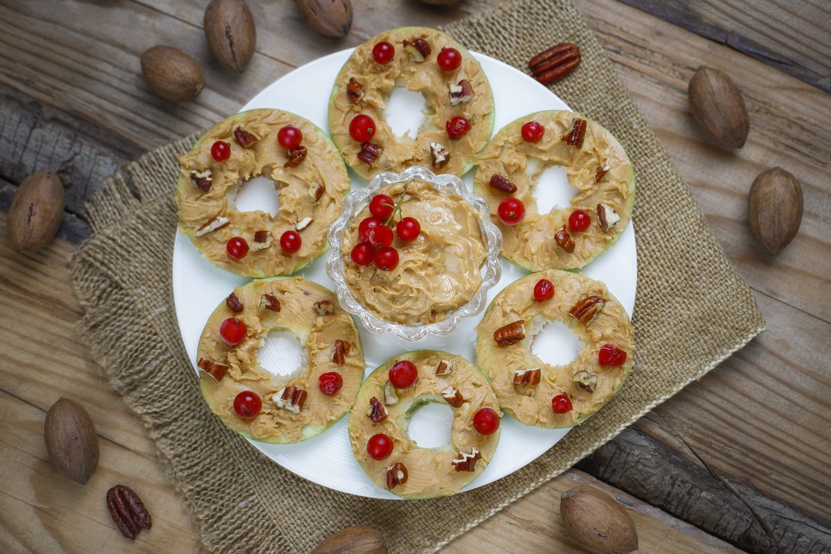 Green apple slices with peanut butter, pecans and redcurrants