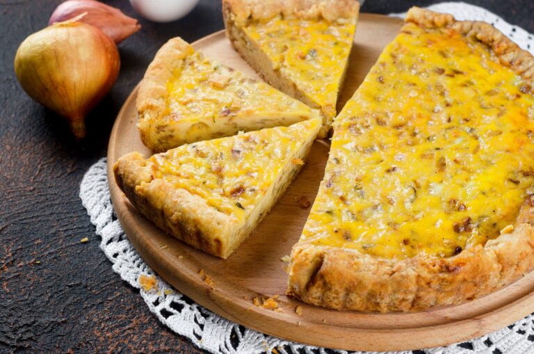 Homemade onion tart cut into slices on a wooden board