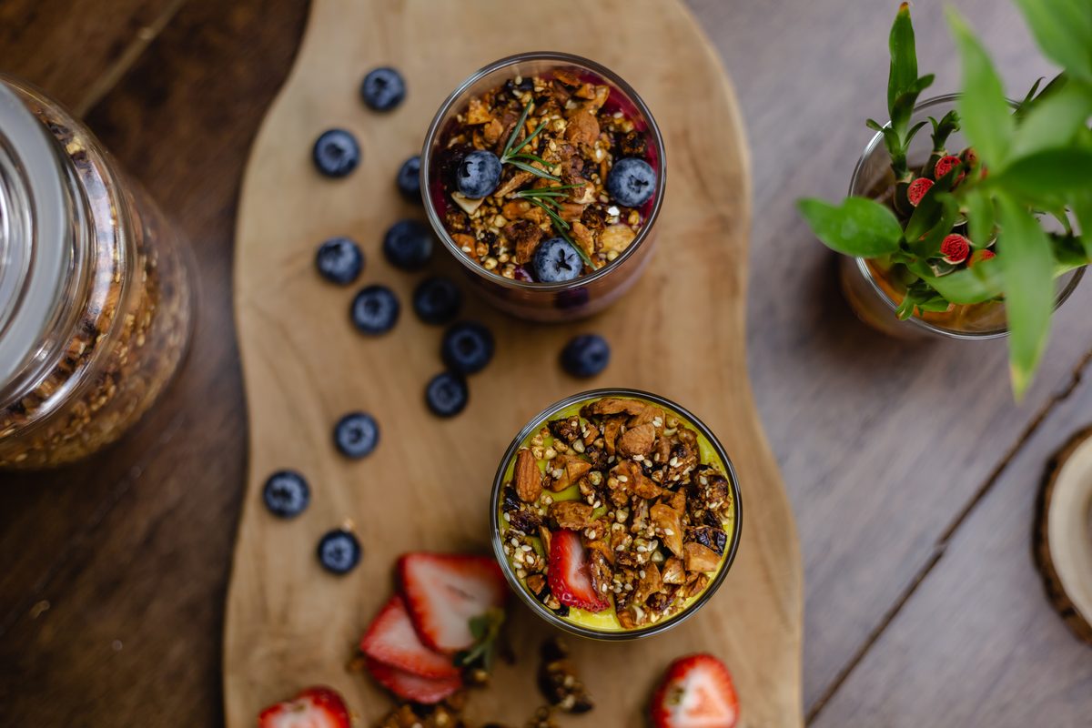 Granola pots with blueberries and strawberries on a wooden board